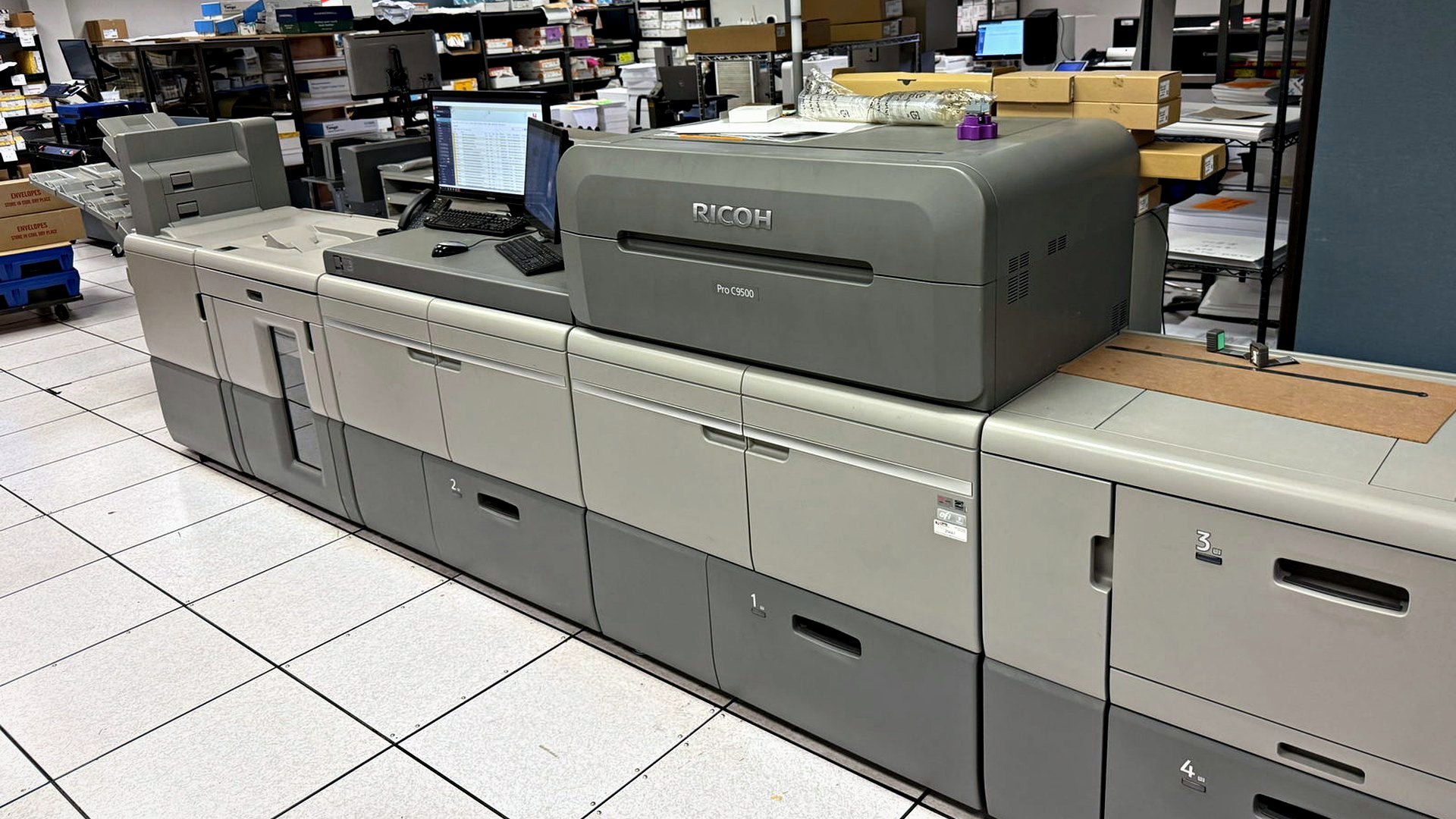 The Ricoh Pro C9500 digital press with its feeder and stacker units at Broudy Printing